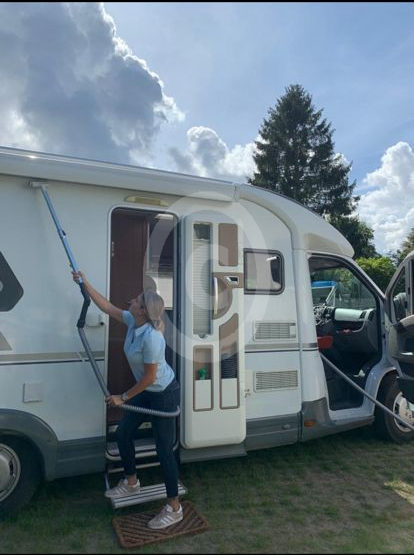 Satubsaugerschlauch zur Wohnmobilreinigung Frau mit Staubsaugerschlauch Staubnatter bei der Außenreinigung des Wohnmobils