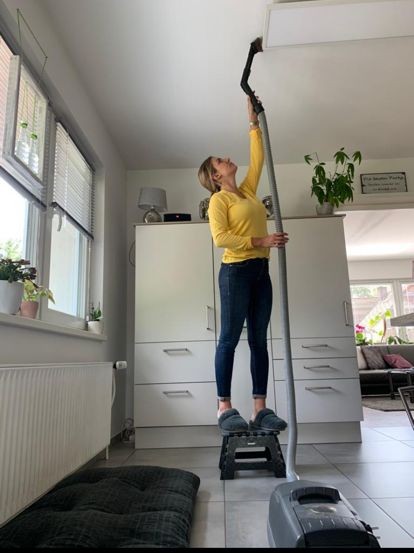Deckenlampensaugen mit Staubsaugerschlauch Frau mit Staubsaugerschlauch beim Deckenlampensaugen