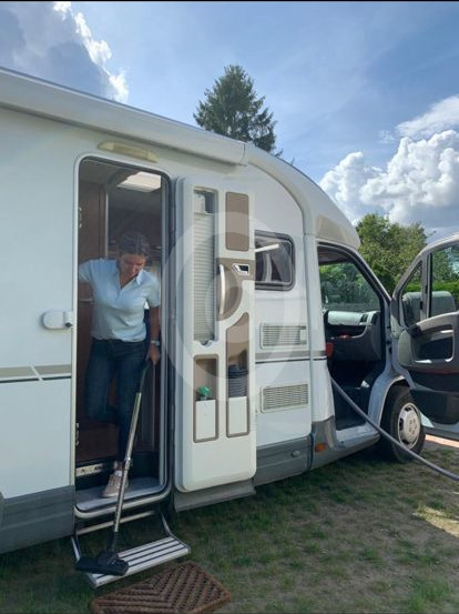Staubsaugerschlauch für Wohnmobilreinigung Frau mit dehnbarem Staubsaugerschlauch bei der Wohnmobilreinigung